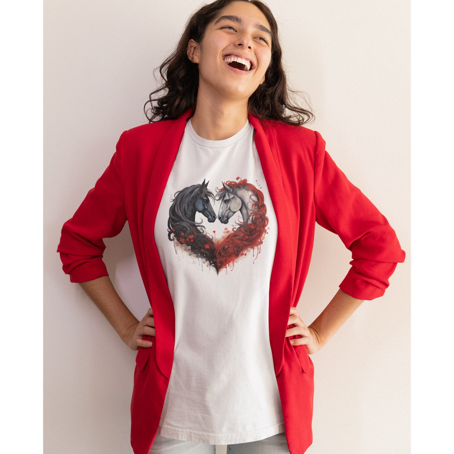 Eine jungen Frau mit einem roten Blazer trägt ein weißes Tshirt mit Pferde Design, der Hintergrund ist grau